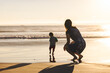 Leinwandbild Motiv Woman Crouching Behind Son Running On Shore