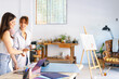 © Westend61 - Female creative professionals discussing at desk in art studio