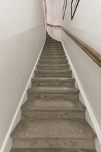 Narrow Gray Stairway With White Walls And Wooden Railing