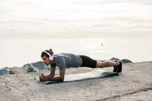 Male Athlete With Headphones Exercising Plank Position On Exercise Mat