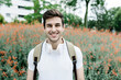 © Westend61 - Smiling young man carrying backpack while standing in front of meadow