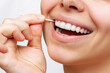 A cropped shot of a young beautiful caucasian woman brushes her teeth with a wooden toothpick after eating isolated on a white background. Oral hygiene, dental health care. Close-up. Dentistry concept