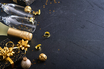 Wall Mural - Holiday gift box or present with ribbon, golden confetti and gold baubles on black background. Magic christmas greeting card. Christmas Decoration. Border design. Mock up. Top view.