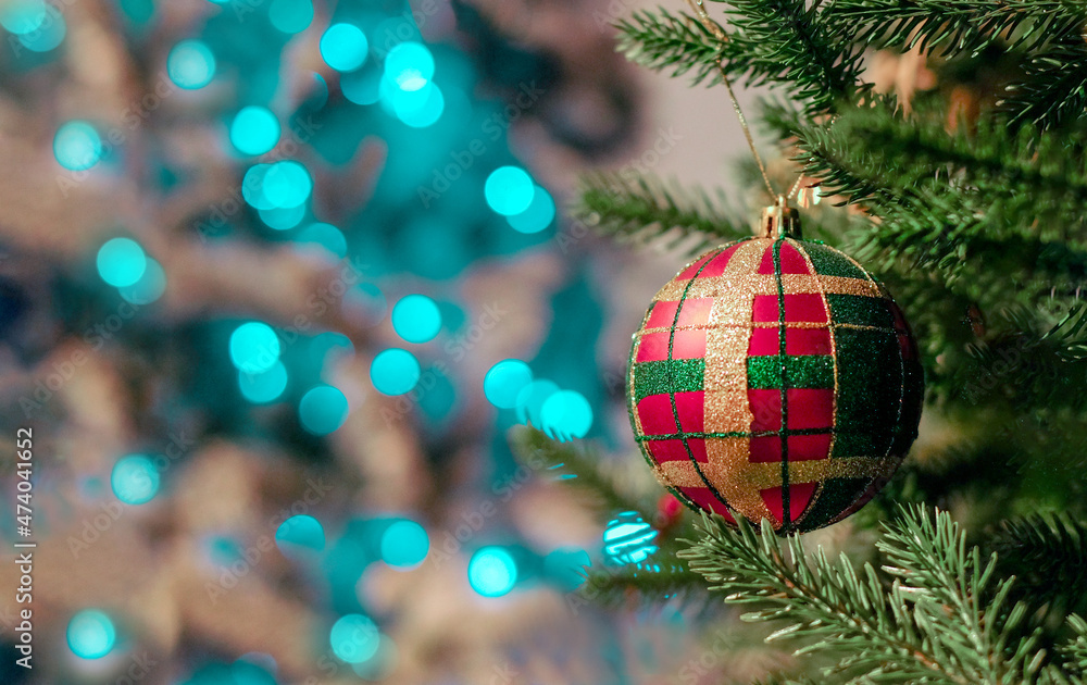 Christmas ball as plaid hangs on a branch of a Christmas tree on bokeh ...