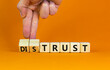 © Dzmitry - Distrust or trust symbol. Businessman turns wooden cubes, changes words 'distrust' to 'trust'. Beautiful orange table, orange background. Business and distrust or trust concept, copy space.