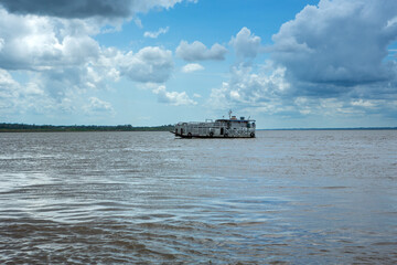 Wall Mural - Beautiful view of Amazon river and wooden motor boat for transporting cattle in sunny summer day with clouds. Manaus, Amazonas, Brazil. Concept of environment, ecology, nature, conservation, travel.