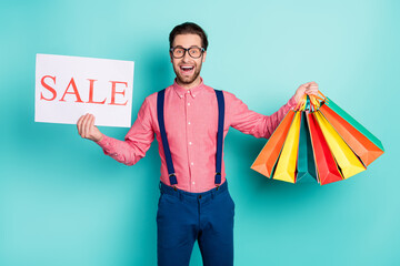 Sticker - Photo of young man happy positive smile hold bags shopper hold banner sale isolated over turquoise color background