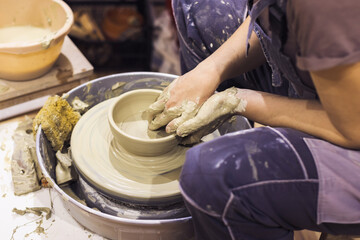 Pottery workshop. Closeup of woman artist hands molding clay on pottery wheel. Creative handmade craft. Ceramic art studio.