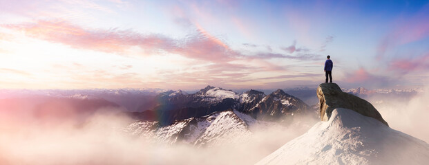 Wall Mural - extreme adventure composite. man on top of a rocky mountain cliff. dramatic sunset. 3d rendering pea