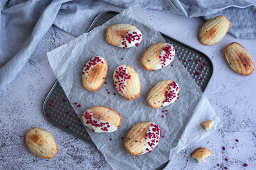 Wall Mural - homemade cookies: madeleine cookies with raspberry slices in a white chocolate glaze on a gray background