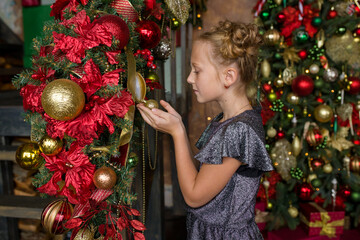 Wall Mural - A little girl with a Christmas present. A girl near the Christmas tree.