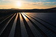 © 24K-Production - Aerial shot of ground-mounted solar panels, on a solar farm, at sunset.