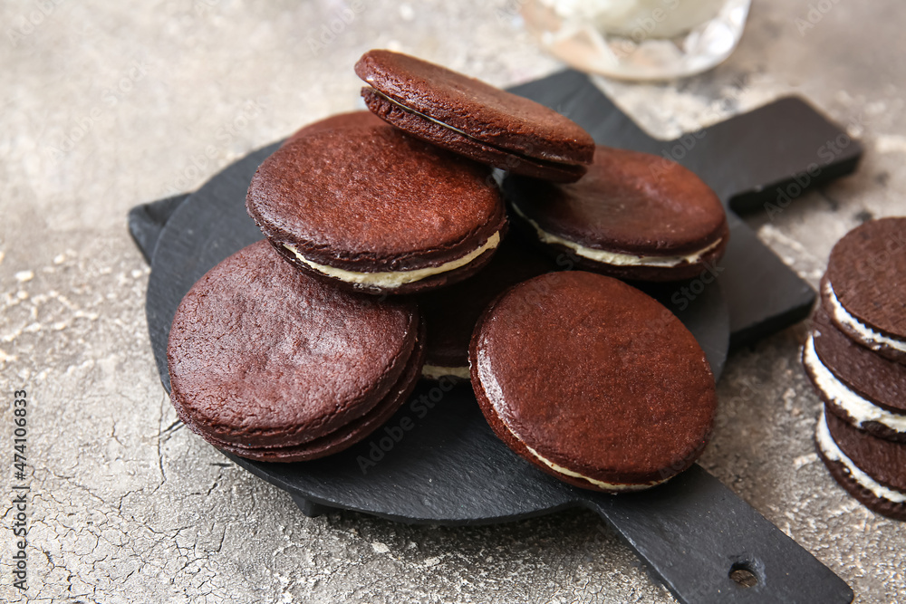 Slate board with tasty chocolate cookies on grey background, closeup