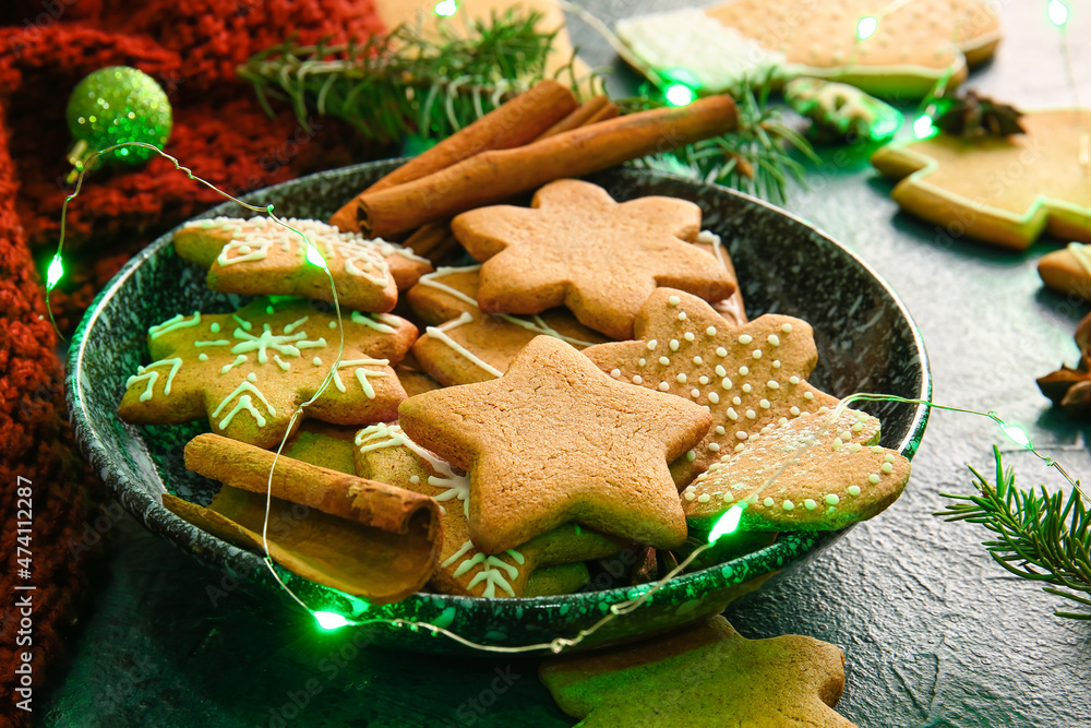 Plate with sweet Christmas gingerbread cookies on black background