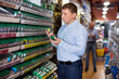 © JackF - Glad cheerful positive smiling male customer choose fasteners and screws at hardware store