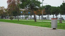 City Park Beside A Street At Thessaloniki, Greece - Static Shot With Dustbin, Trees, Bird And People At Park Bench
