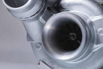 Wall Mural - Close-up of an auto part for an internal combustion engine. Gas turbine. Turbo supercharger new on a gray background. Parts background