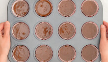 Chocolate Cupcakes Recipe. Cupcake Pan Lined With Paper Liners, And Silicon Molds Filled With Chocolate Cake Batter, Close Up View Directly From Above, Woman Hands