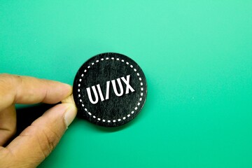 hand holding a circle with the words UI and UX letters or User Interface and User Experience