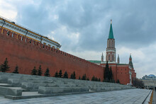 The Red Kremlin Wall And Nikolskaya Tower On Red Square In Moscow. Leaden Sky In The Background. A Monument Of Architecture.