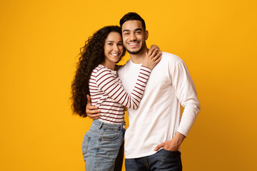 Wall Mural - Romantic Couple. Happy Middle Eastern Man And Woman Embracing On Yellow Background