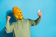 Photo Of Lucky Strong Guy Dressed Wild Animal Mask Tacking Selfie Modern Device Rising Fist Isolated Blue Color Background