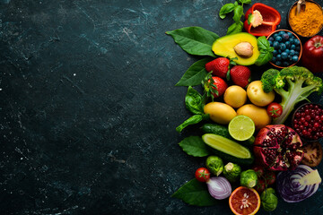 Wall Mural - Organic vegan food: fresh vegetables and fruits are good for health. On a black stone background.