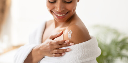 Wall Mural - African Woman Applying Lotion On Shoulders Moisturizing Skin In Bathroom