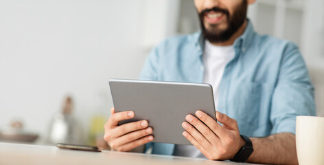 Wall Mural - Young man using digital tablet, browsing internet or reading news, enjoying weekend and resting at home