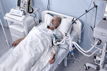 Sick Senior Caucasian Man Has Blood Transfusion In Hospital, Patient With Tube In Mouth. Ill Male 60-70 Years Old Suffering From Coronavirus, Covid-19. Man Lying On Bed In Private Room
