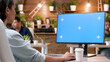 © DC Studio - Businesswoman sitting at desk looking at mock up green screen chroma key computer with isolated display analyzing marketing project ideas. Manager woman working at company strategy in startup office