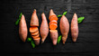 Raw organic sweet potatoes on a wooden background. Dietary food. Top view.