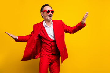 Photo of good mood funky middle age male dancing in red tuxedo sunglass feeling young isolated on yellow color background