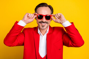 Poster - Portrait of young cheerful well-dressed man in sunglass enjoy summer wear red tuxedo isolated on yellow color background