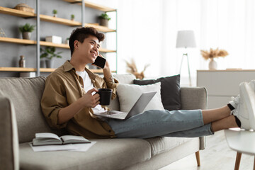 Smiling asian man working and talking on phone at home