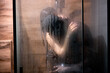 © alfa27 - soft focus. naked young african man and caucasian woman take shower together, view through the bathroom window. love, sexual and intimate life. honeymoon. side view portrait. copy space.