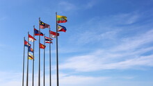  ASEAN Flags Flying On Poles. Several Multicolored ASEAN Flags On Metal Poles Flutter In The Wind Against The Backdrop Of A Blue Sky With Thin White Clouds With Copy Space. Selective Focus
