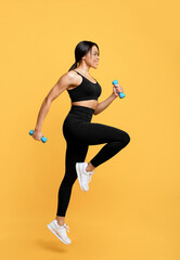 Wall Mural - Workout concept. Full length shot of young black woman in sportswear exercising with two dumbbells, yellow background