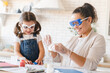 Funny chemistry. Scientific experiment at home. Laboratory tests for school homework. Parent mother with daughter kid making chemical test at home kitchen.