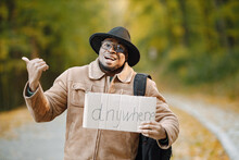 Black Man Hitchhiking On A Road And Holding A Cardboard Sign Anywhere