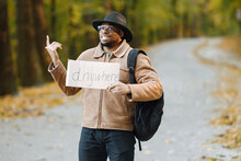 Black Man Hitchhiking On A Road And Holding A Sign Anywhere