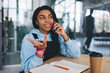 © BullRun - Black girl talking on mobile phone at desk