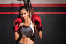 Portrait Of Attractive Asian Woman In Sportswear Wear Red Boxing Gloves With Workout And Pose Boxing Show Punch In Gym.