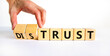 Distrust or trust symbol. Businessman turns wooden cubes, changes words 'distrust' to 'trust'. Beautiful white table, white background. Business and distrust or trust concept, copy space.