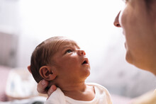 Portrait Of Serious Newborn Baby Looking At His Mother.