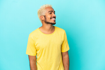 Canvas Print - Young Colombian handsome man isolated on blue background looking side