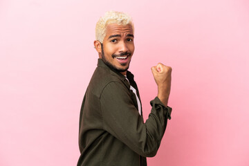 Poster - Young Colombian handsome man isolated on pink background doing strong gesture