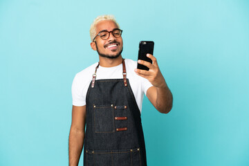 Wall Mural - Restaurant Colombian waiter man isolated on blue background making a selfie