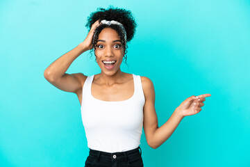 Sticker - Young latin woman isolated on blue background surprised and pointing finger to the side