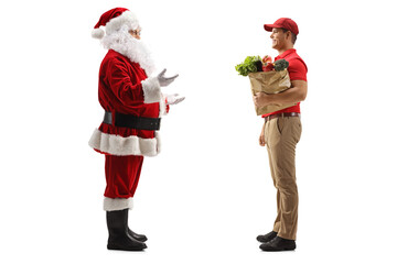 Wall Mural - Full length profile shot of santa claus talking to a delivery man with a grocery bag